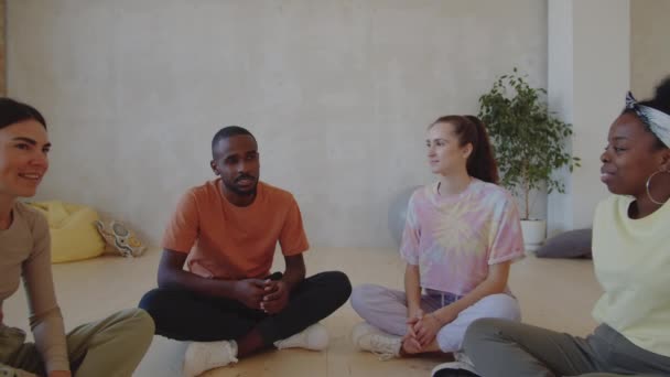 ズームアウトショットのチームの若い多民族男性と女性ダンサーの床の上にスタジオに座って話す — ストック動画