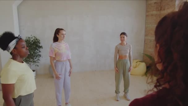 スタジオでダンス教室の前で暖まりながら肩円を描く若い多民族男女の円弧撮影 — ストック動画