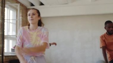 Stüdyodaki koreografi dersinde gülümseyen ve dans eden pozitif etnik gruptan oluşan bir grup.