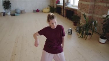 Stüdyoda dans eden genç bayan dansçının yüksek açılı çekimi.