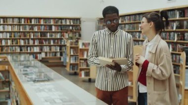 Genç Afro-Amerikalı bir adam kitap okuyor ve bunu kütüphanede birlikte dururken beyaz bir bayan arkadaşla tartışıyor.