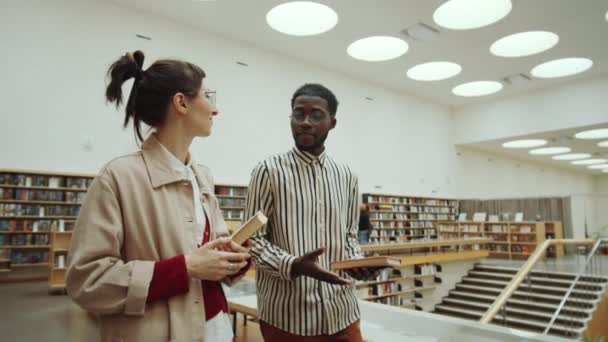 Jovem Afro Americano Caminhando Com Amiga Caucasiana Através Biblioteca Leitura — Vídeo de Stock