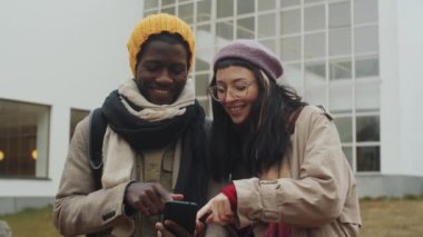 Çok ırklı genç bir çift şehrin dışında dikiliyor, gülümsüyor ve akıllı telefondan güzergahı tartışıyorlar.