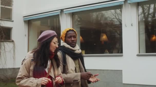 年轻的多民族男子和妇女穿着外衣在街上散步 边聊天边在城市里同行 — 图库视频影像