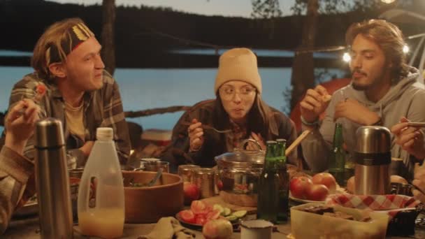 Panorámica Jóvenes Amigos Alegres Sentados Juntos Mesa Bajo Guirnalda Cenando — Vídeos de Stock