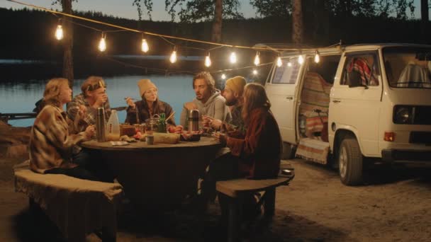 Grupo Hombres Mujeres Jóvenes Sentados Juntos Mesa Bajo Guirnalda Comiendo — Vídeos de Stock