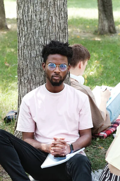 Afrikanischer Student sitzt im Park — Stockfoto