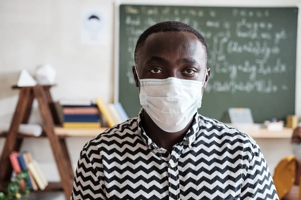 Teacher in mask standing at school