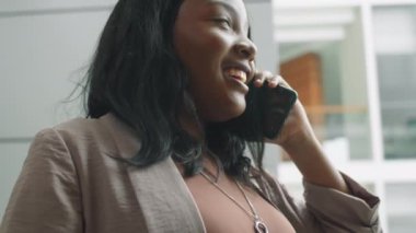 Güzel Afro-Amerikalı iş kadınının ofis merkezinde cep telefonuyla konuşurken yakın plan görüntüsü.
