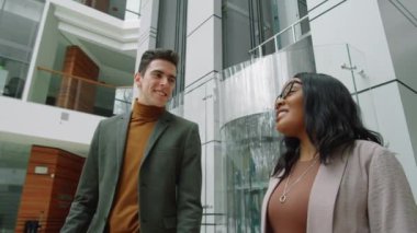 Beyaz iş adamının siyahi bir iş arkadaşıyla ofiste yürümesi ve onunla konuşması düşük açılı.