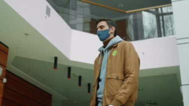 Coronavirus salgını sırasında ofis merkezine sipariş verirken maskeli ve eldivenli bir kuryenin Afro-Amerikalı iş kadınına kese kağıdı verdiği düşük açılı fotoğraf.