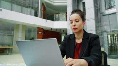 Modern ofis merkezinde çalışırken dizüstü bilgisayarda yazı yazan melez bir iş kadını.