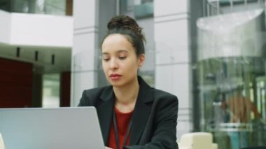 Modern ofis merkezinde çalışırken masa başında oturup dizüstü bilgisayar kullanan güzel bir ırk işkadını.