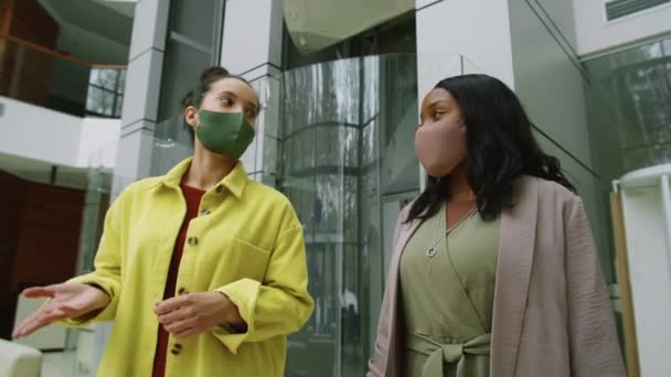 两名戴口罩的多族裔女商人在办公室中心散步 在Covid 19疫情爆发期间边工作边讨论的低角度镜头 — 图库视频影像