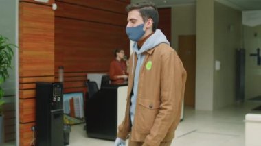 Maskeli ve eldivenli kurye Afro-Amerikalı iş kadınına kağıt torba verirken aynı zamanda Covid-19 salgını sırasında ofis merkezine yemek götürüyordu.