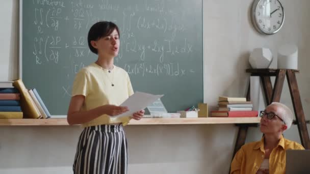 Joven Estudiante Pie Junto Pizarra Aula Leyendo Texto Papel Delante — Vídeos de Stock