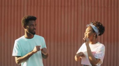 Sokakta gülümseyen ve dans eden genç Afro-Amerikan erkek ve kadınların belden aşağı vuruşlarını çek.