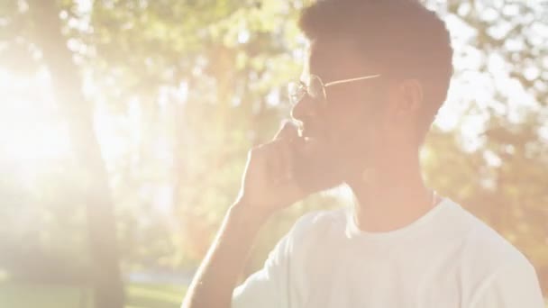 Молодой Афроамериканец Гуляющий Парке Солнечный Летний День Разговаривающий Мобильному Телефону — стоковое видео