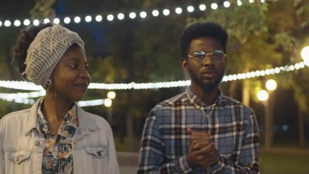 年轻快乐的非洲裔美国人朋友们晚上一起在公园散步时微笑着聊天 — 图库视频影像