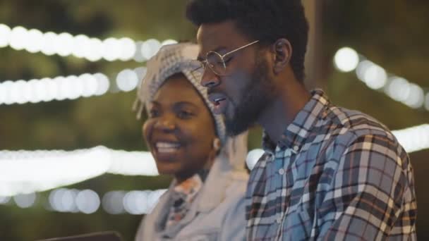 Ung Afro Amerikansk Man Och Kvinna Sitter Bänk Parken Kvällen — Stockvideo