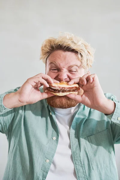 Man met overgewicht die hamburger eet — Stockfoto