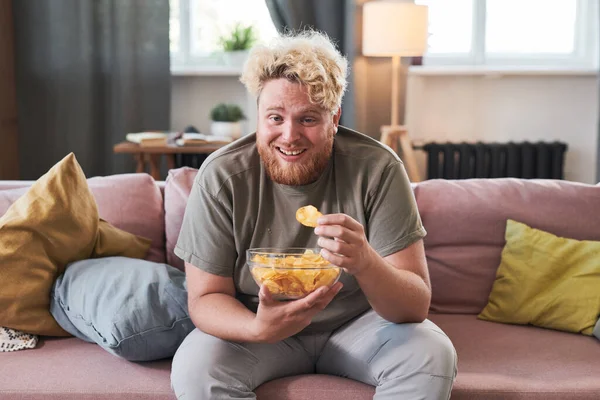 Uomo mangiare patatine mentre guarda la TV — Foto Stock