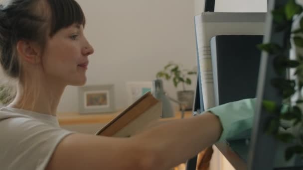 Vue Latérale Jeune Femme Caucasienne Gants Caoutchouc Essuyant Poussière Bibliothèque — Video