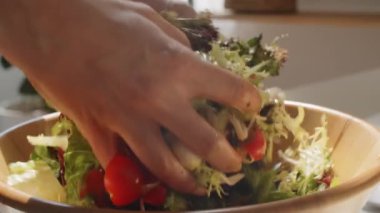 Sebze salatasıyla ahşap kasede mozarellayı karıştıran tanınmayan kadının ellerini yakın plan çek.