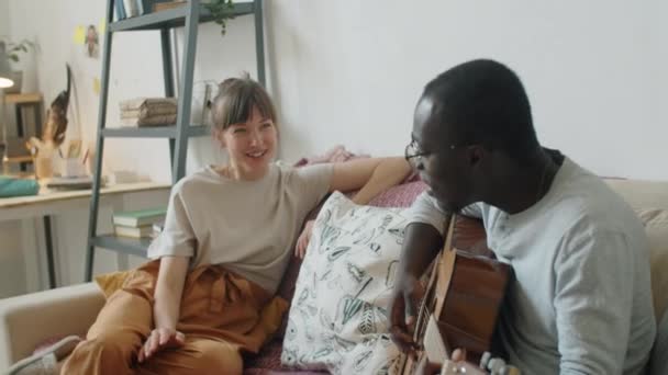 Junge Kaukasierin Sitzt Auf Sofa Und Singt Mit Afroamerikanischem Ehemann — Stockvideo