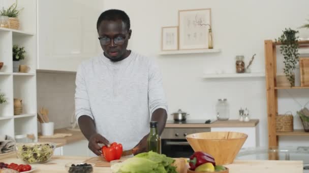 Joven Afroamericano Cortando Pimiento Fresco Mesa Cocina Mientras Cocina Ensalada — Vídeo de stock