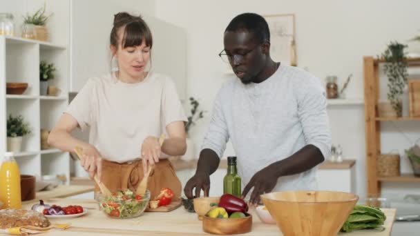 Joven Pareja Multiétnica Preparando Ensalada Verduras Juntos Hablando Mientras Cocina — Vídeo de stock