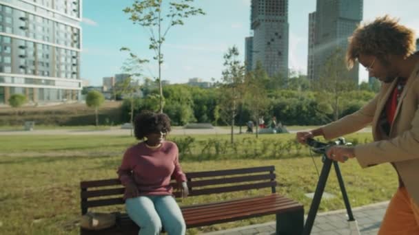 젊은아 미국인 공원에서 스쿠터를 일어나고 벤치에 친구와 잡담을 — 비디오