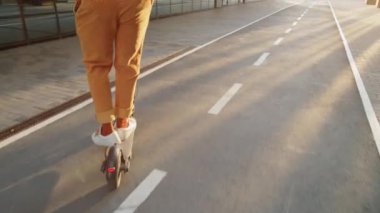Afro-Amerikalı bir adamın sabahın köründe elektrikli scooter sürerken çekilen görüntüsü.