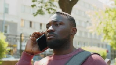 Yazın parkta cep telefonuyla konuşan Afro-Amerikalı bir genç.