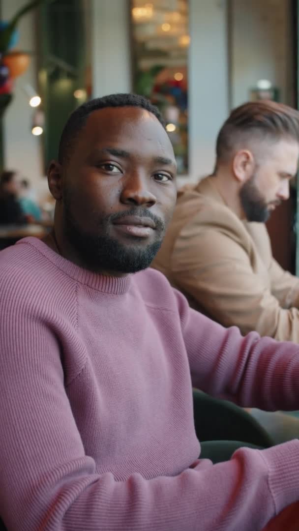 Вертикальный Портрет Молодого Афроамериканца Смотрящего Камеру Улыбающегося Сидя Кафе — стоковое видео