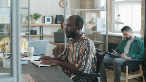 장애가 아프리카 미국인 사업가가 동료들 사무실에서 일하는 휠체어에 컴퓨터로 모습이 — 비디오