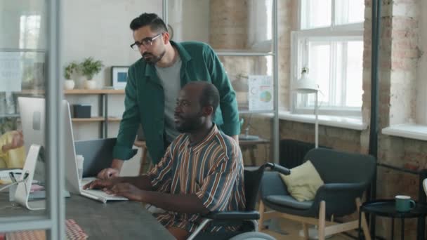 휠체어에 장애가 아프리카 미국인 동료가서 사업가와 사무실에서 일하는 컴퓨터 화면으로 — 비디오