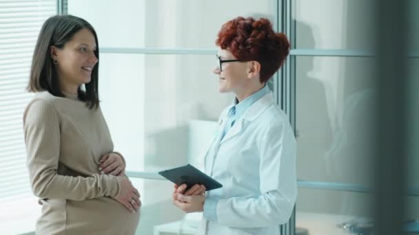 提起孕妇和女医生说话的照片 然后站在诊所里看着镜头 — 图库视频影像