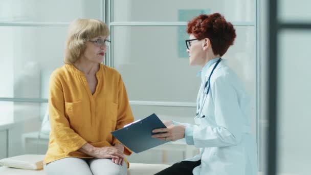 Oudere Vrouw Jonge Vrouwelijke Arts Zitten Samen Medische Bank Bespreken — Stockvideo
