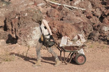 Mülteci dışarıda el arabası taşıyor.