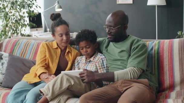 Padres Afroamericanos Hijo Pequeño Sentados Juntos Sofá Casa Sonriendo Usando — Vídeos de Stock