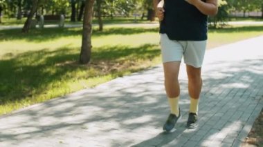 Yaz günü spor giyim kuşağında parkta koşan terli, kilolu adamı yukarı kaldır.