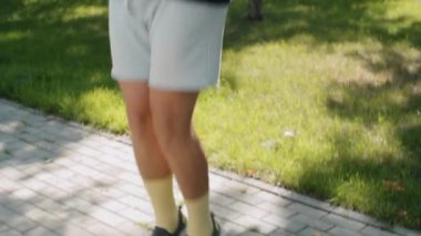 Spor giyim giymiş obez bir adamın parkta kilo verme antrenmanı yaparken halattan atlarken çekilen görüntüsü.