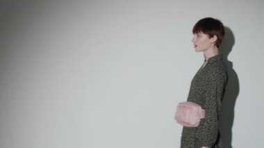 Beyaz arka planda kameraya poz verirken gülümseyen ve alışveriş torbalarını kaldıran güzel beyaz kız.