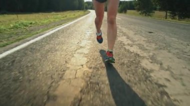 Güneşli yaz gününde antrenman yaparken asfalt yolda koşan sporcu kadının bacaklarının düşük kesiminden.