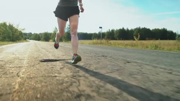 夏の晴れた日にマラソンのための訓練中にアスファルトの道路上で実行されているスポーツウェアで女性のトライアスロン選手のショットを傾ける — ストック動画