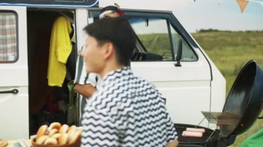 Orta Doğulu yemek kamyonu satıcısı yaz festivalinde müşteriler için sosisli pişirirken sosis pişiriyor.