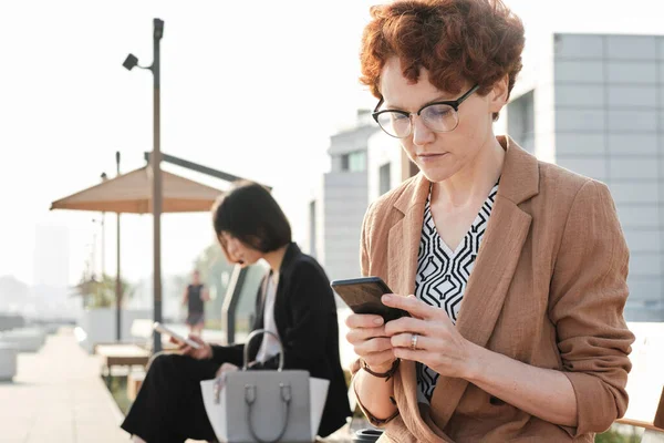 Geschäftsfrau sitzt mit Smartphone im Freien — Stockfoto
