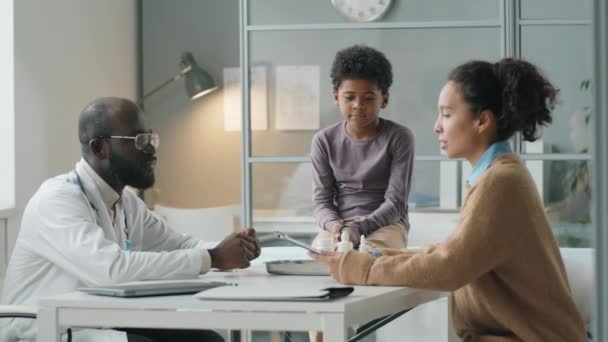 Афроамериканский Педиатр Разговаривает Женщиной Маленьким Сыном Время Консультации Медицинском Кабинете — стоковое видео
