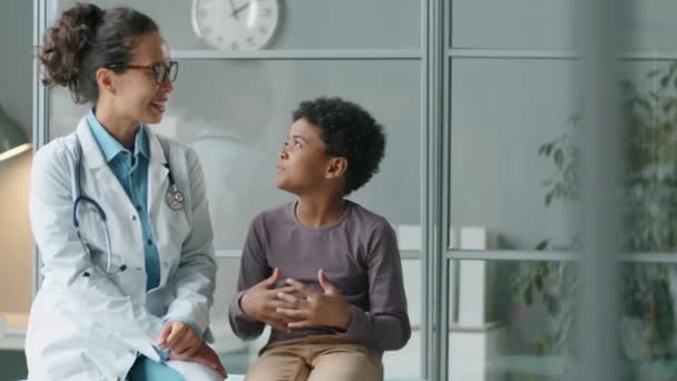 Sledování Záběru Malého Afroamerického Chlapce Doktorky Sedí Spolu Gauči Klinice — Stock video